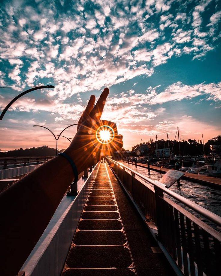 A photo of someone looking at the sunset through their fingers.